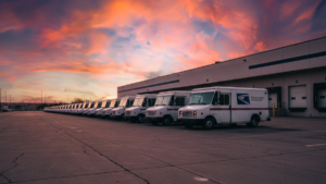 A line of stationary USPS long-life vehicles parked at a distribution center during the 2026 Presidents Day holiday.